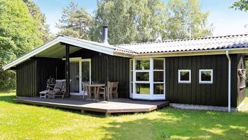A wooden cabin with a covered porch, a chimney, and a small deck.