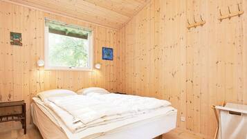 A wooden room with a bed, a window, and a wall-mounted coat rack.