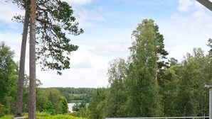 A deck with outdoor furniture overlooking a river and forest. - 4 Person Holiday Home in Boras (Borås)