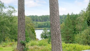 A natural landscape with two prominent trees, a bench, and a lake in the background. - 4 Person Holiday Home in Boras (Borås)