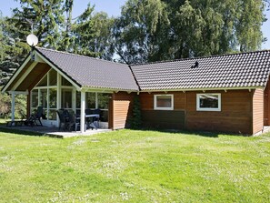 A single-story house with a covered patio area, a satellite dish, and a small garden. - 5 Star Holiday Home in Hojby (Hojby)
