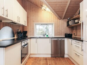 Une cuisine moderne avec des murs en bois, une fenêtre et des appareils électroménagers en acier inoxydable.