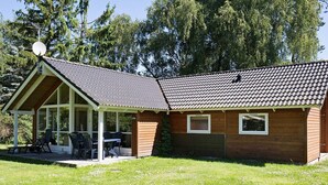 A single-story house with a covered patio area, a satellite dish, and a lawn.