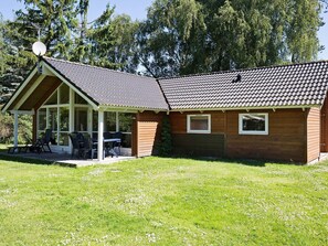 A single-story house with a covered patio area, a satellite dish, and a lawn. - 5 Star Holiday Home in Hojby (Hojby)