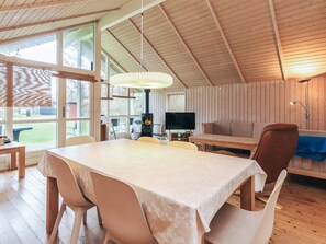 A cozy room with a dining table, chairs, a sofa, a television, and a fireplace. - 5 Star Holiday Home in Hojby (Hojby)