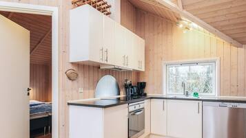 Ett modernt kök med vita skåp, en ugn i rostfritt stål och en diskmaskin.