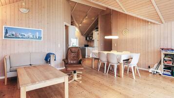 A wooden interior with a dining area, a sofa, and a table.