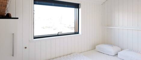 A bedroom with a single bed, a window with blinds, and a white wall.
