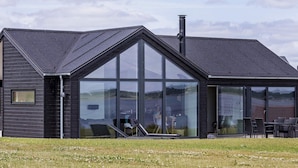 Een modern gebouw met grote glasramen, een schuin dak en een schoorsteen.