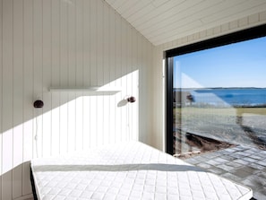 Una habitación con cama, ventana y vista al mar.