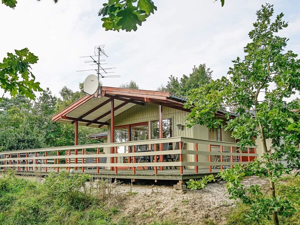 A wooden cabin with a balcony, surrounded by trees. - 6 Person Holiday Home in Aakirkeby (Akirkeby)