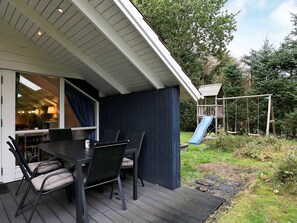 A covered patio with a table and chairs, a slide, and a play structure. - 4 Star Holiday Home in Hals (Hals)