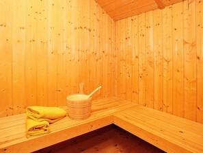 A sauna room with wooden walls and a bench.