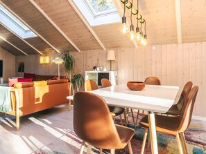 A modern living room with a wooden ceiling, a dining table with chairs, a sofa, and a lamp. - Secluded Retreat in Koldkaer (Hals)