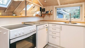Eine moderne Küche mit integriertem Backofen, Kochfeld, Spüle und einem Fenster mit Blick auf einen Garten.