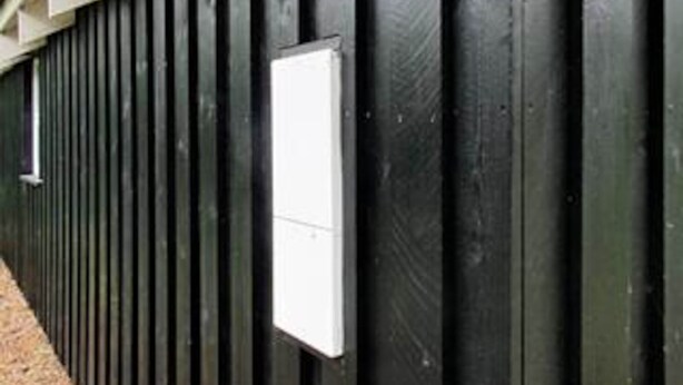 Una pared de metal negro con un objeto rectangular blanco adherido.