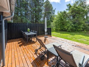 Une terrasse en bois avec une table et des chaises, un parasol et un barbecue.
