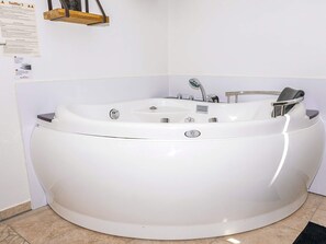 Un grand jacuzzi blanc, autonome, doté d’un panneau de commande, d’un robinet et d’un siège.