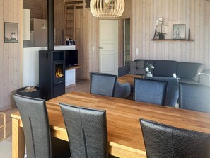 A modern interior with a wooden dining table, black leather chairs, a built-in fireplace, and a sofa.