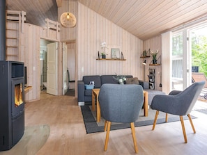 A cozy living room with a fireplace, grey sofas, wooden flooring, and a large window. - 6 Person Holiday Home in Hals (Hals)