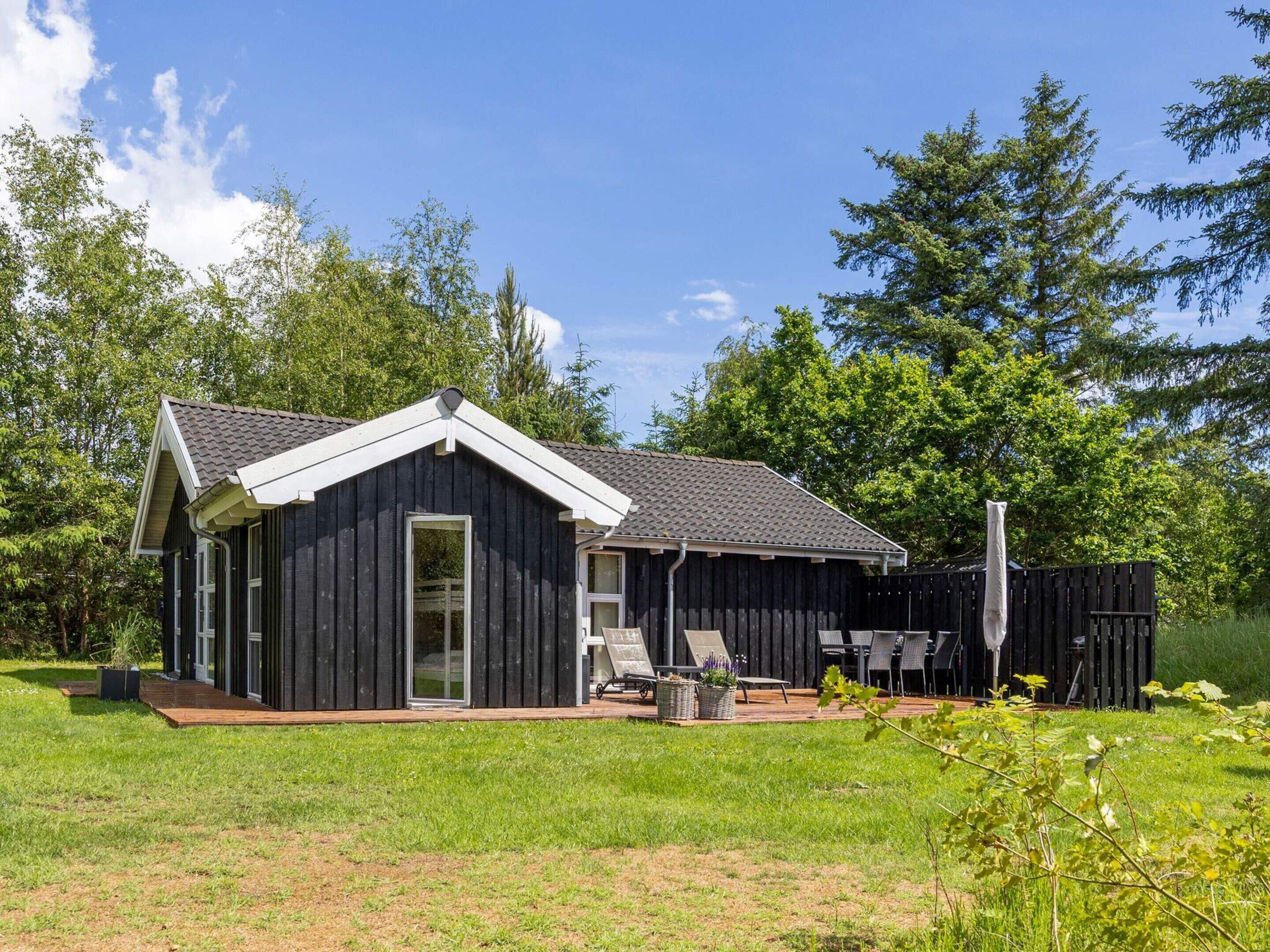 A single-story building with a dark exterior, a sloped roof, and a large sliding glass door.