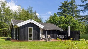 A single-story building with a dark exterior, a sloped roof, and a large sliding glass door.