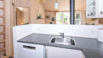 A compact kitchen with a built-in dishwasher, a sink, and a stove.