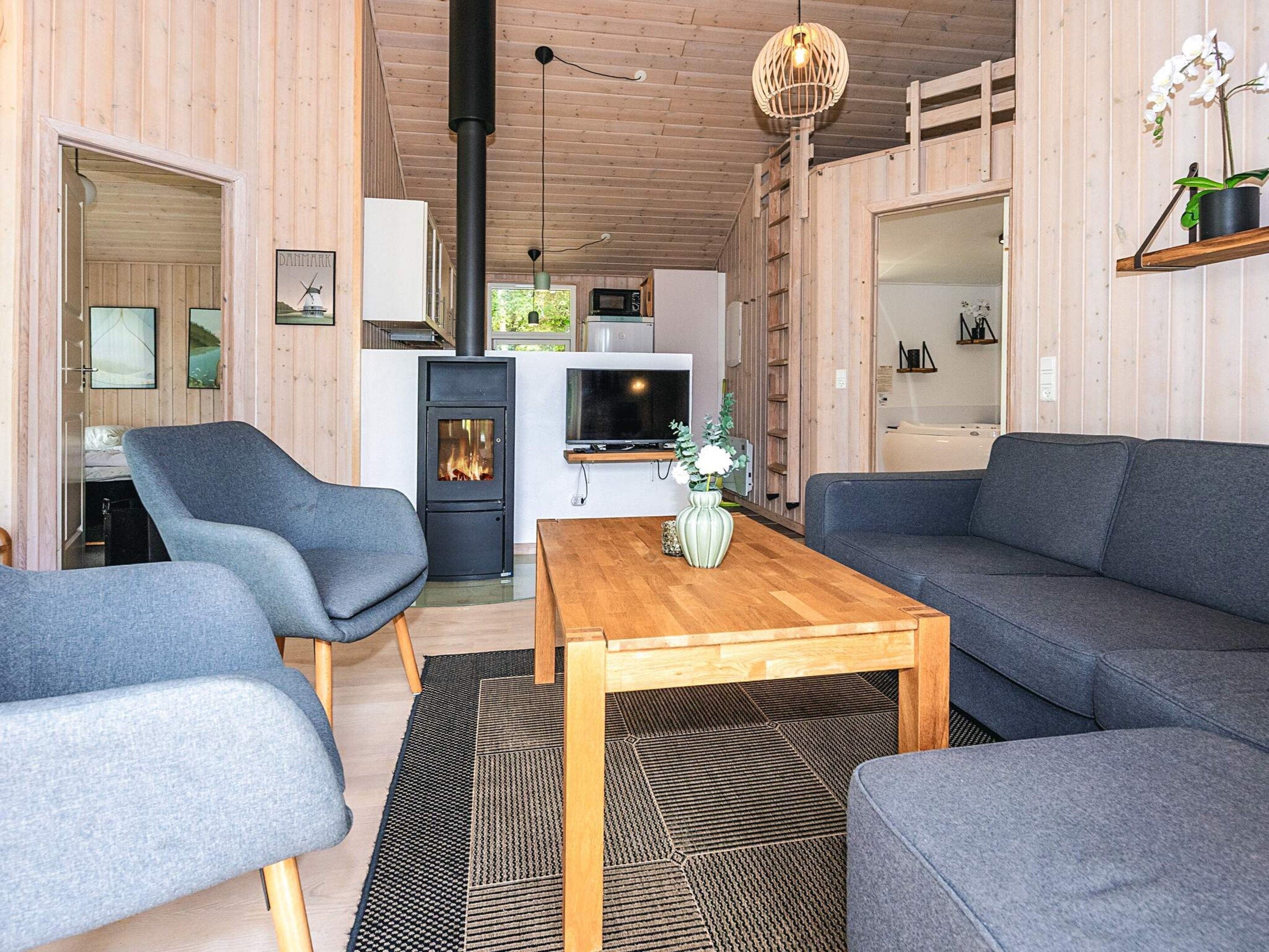 A modern interior with a sofa, chairs, a wooden coffee table, a TV, and a fireplace.