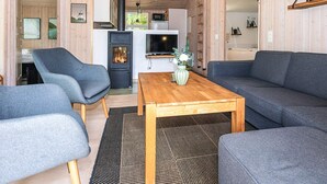 A modern interior with a sofa, chairs, a wooden coffee table, a TV, and a fireplace.