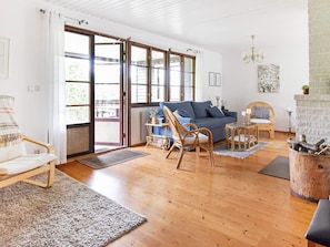Un salon spacieux avec un canapé, des fauteuils, une cheminée et de grandes fenêtres.