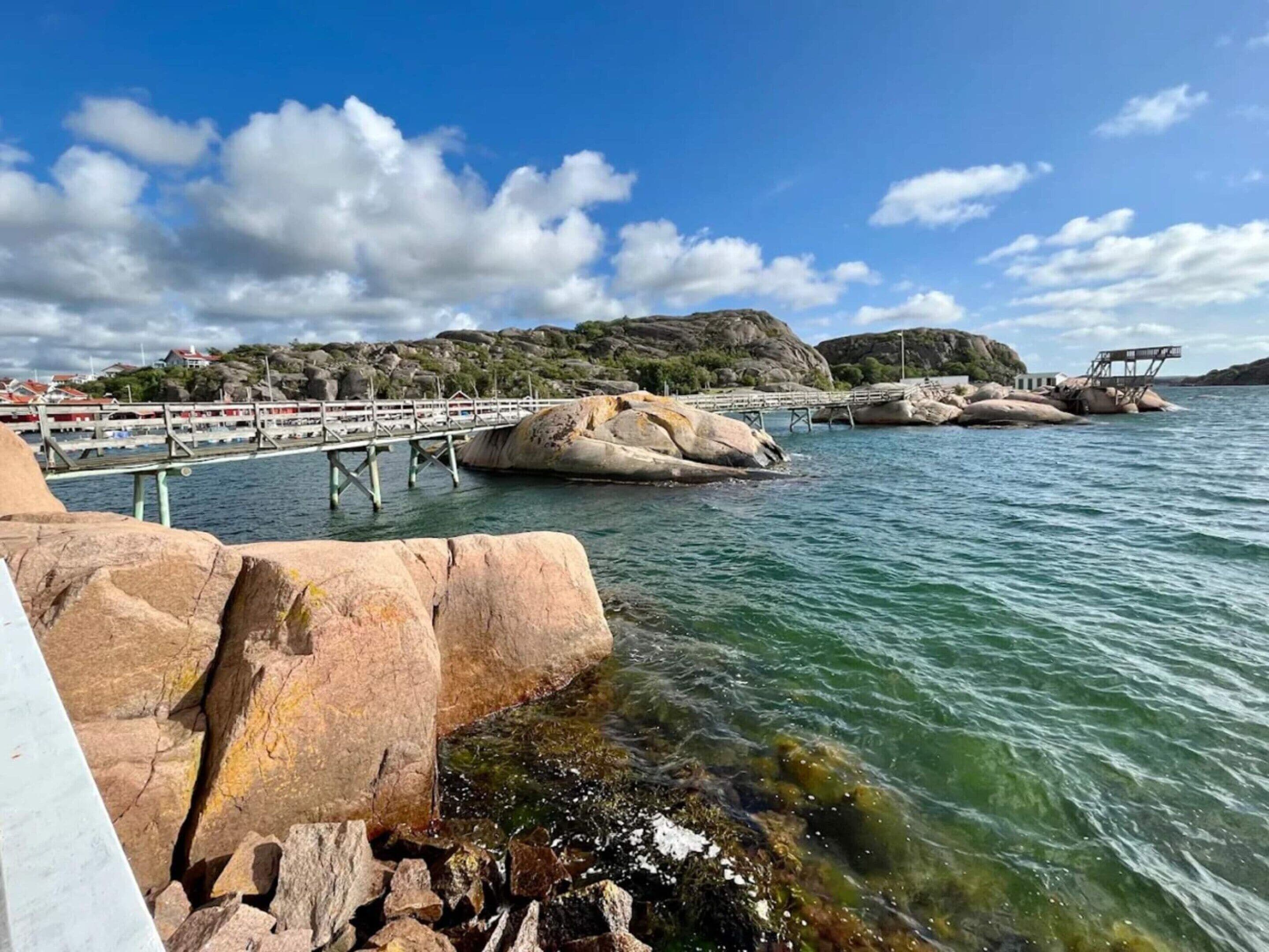 A coastal scene with a pier, rocky shoreline, and clear blue sky.