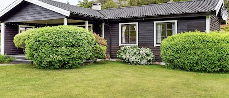 A two-story house with a dark exterior, a sloped roof, and a well-maintained lawn.