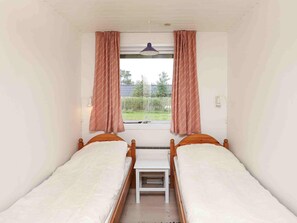 A room with two single beds, a small table, and a window with curtains. - 6 Person Holiday Home in Ulfborg (Ulfborg)