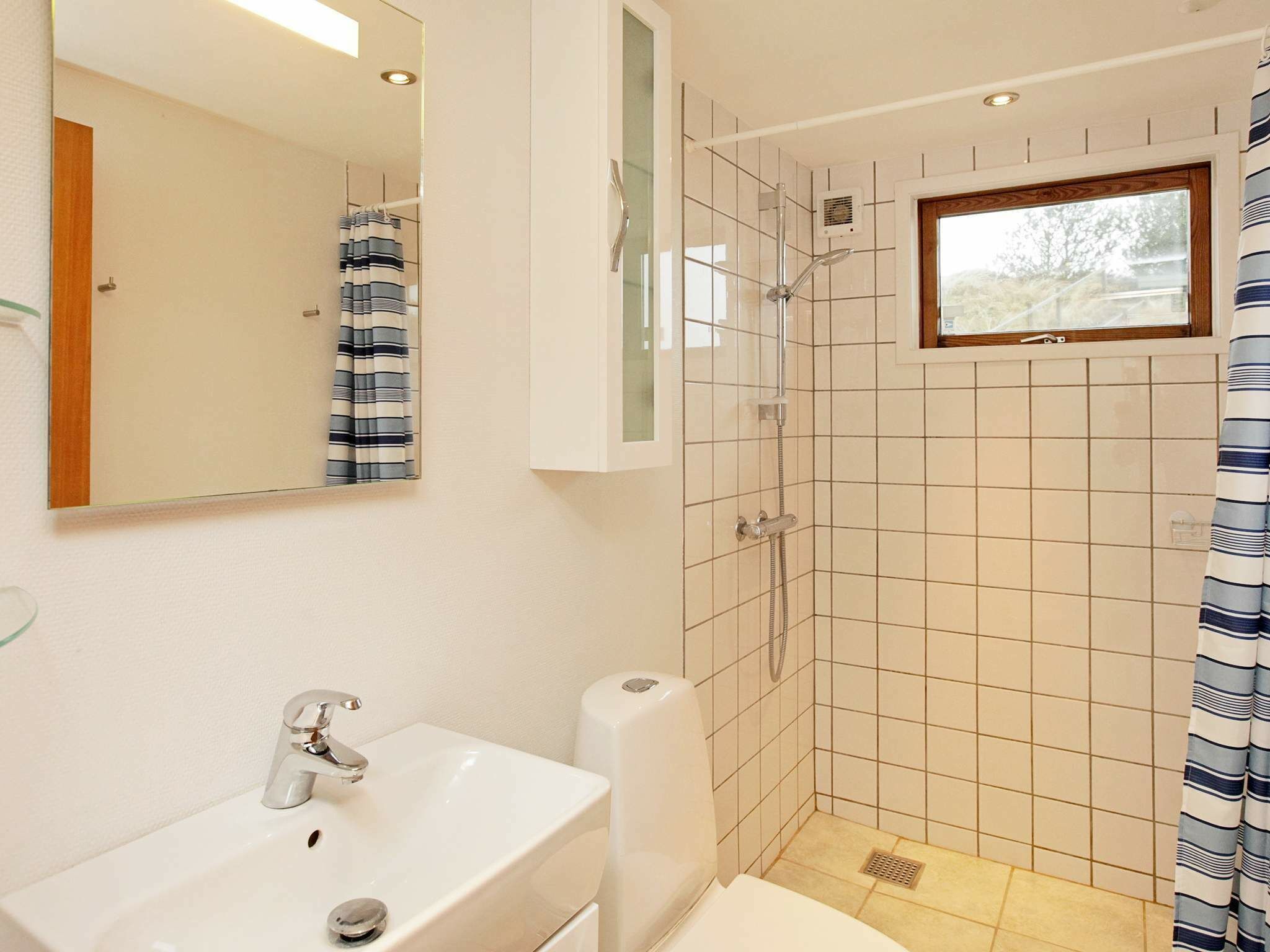 A bathroom with a white sink, mirror, and shower.