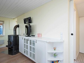Cozy retreat with stove, storage cabinet, and shelf for personal touches.