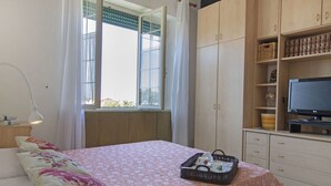 A bedroom with a bed, a desk, a TV, and a window with curtains. - Beautiful apartment for 4 people with WIFI, TV and terrace (Pietrasanta)