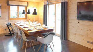 A modern dining area with a wooden table set for four, surrounded by chairs. - Cosy apartment in villa for 10 guests with WIFI, TV and balcony (Randogne)