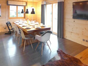 Un comedor moderno con una mesa de madera dispuesta para cuatro personas, rodeada de sillas.