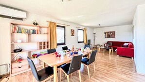 A modern living room with a dining area, a red sofa, a bookshelf, and a television. - Cosy apartment in villa for 4 people with WIFI, A/C, TV, terrace and pets allowed (Bad Wildungen)