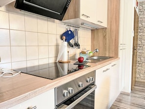 Una cocina moderna con horno empotrado, pileta de acero inoxidable y encimera de madera.
