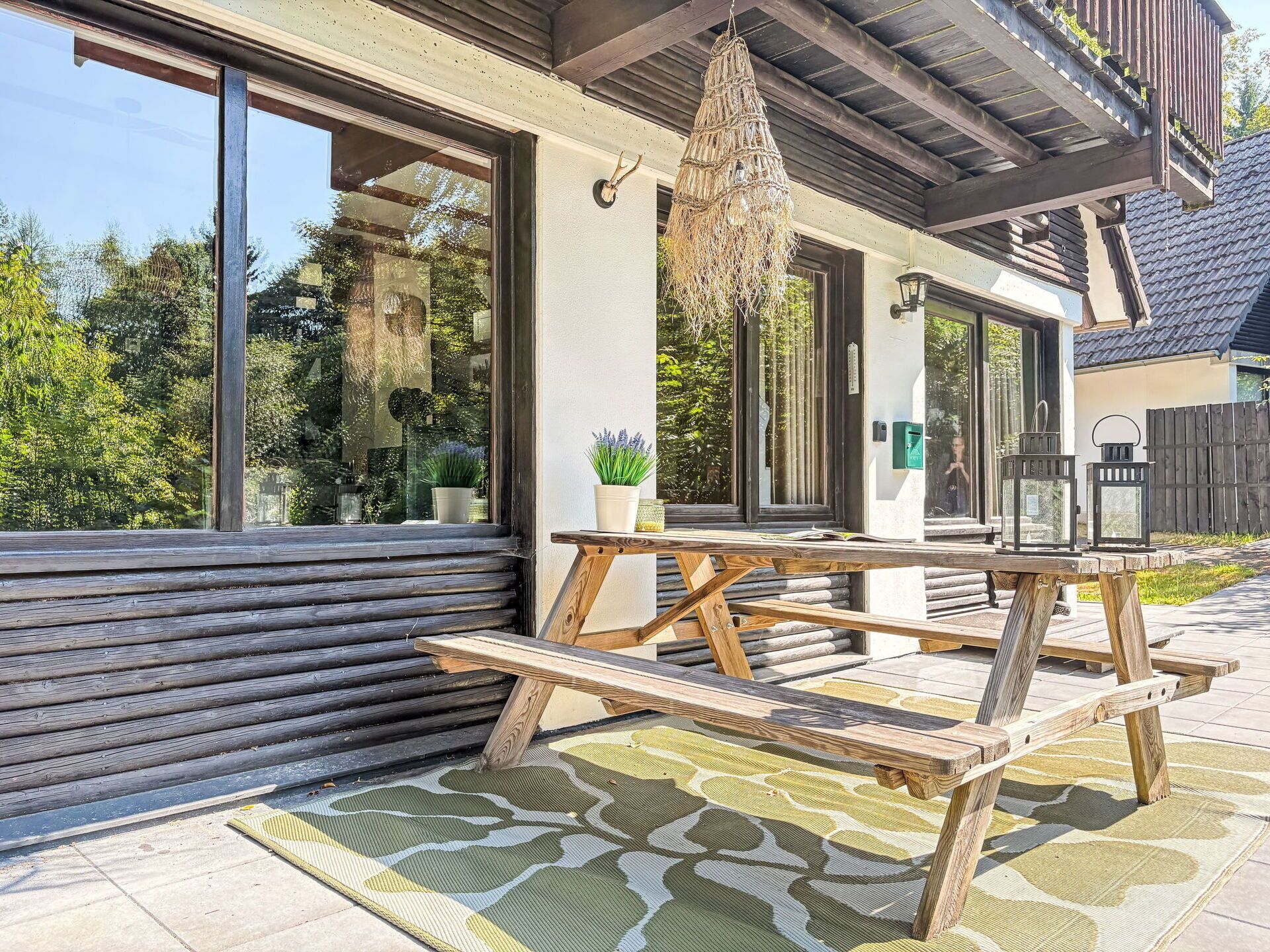 Une terrasse en bois avec une table de pique-nique, des plantes en pot et un luminaire suspendu.