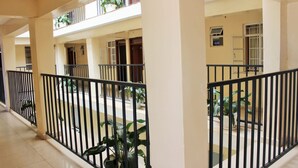 Um corredor com piso ladrilhado, corrimãos pretos e plantas em vasos.