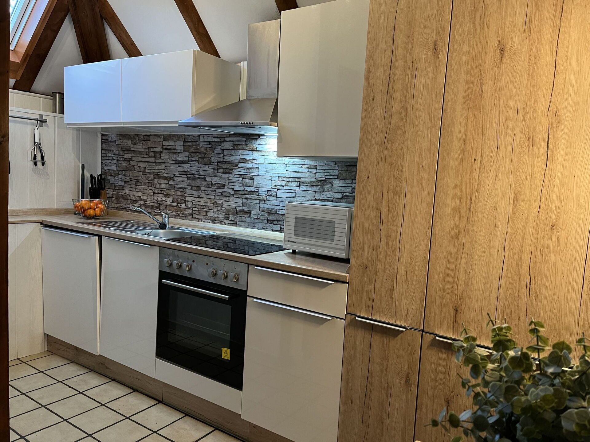 A modern kitchen with white cabinets, a stone backsplash, and a built-in oven.