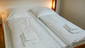 A double bed with white linens and towels, wooden headboard, and a wall-mounted light. - Nice apartment in villa for 6 guests with WIFI, TV, terrace and pets allowed (Bad Wildungen)