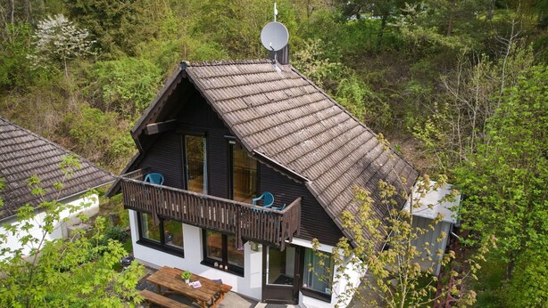 A two-story house with a balcony, satellite dish, and a small shed.