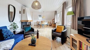 A living room with a sofa, chairs, a coffee table, a fireplace, a television, and a bookshelf.