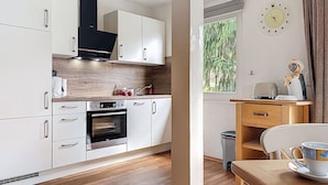 Een moderne keuken met witte kasten, een inbouwoven en een houten aanrecht.