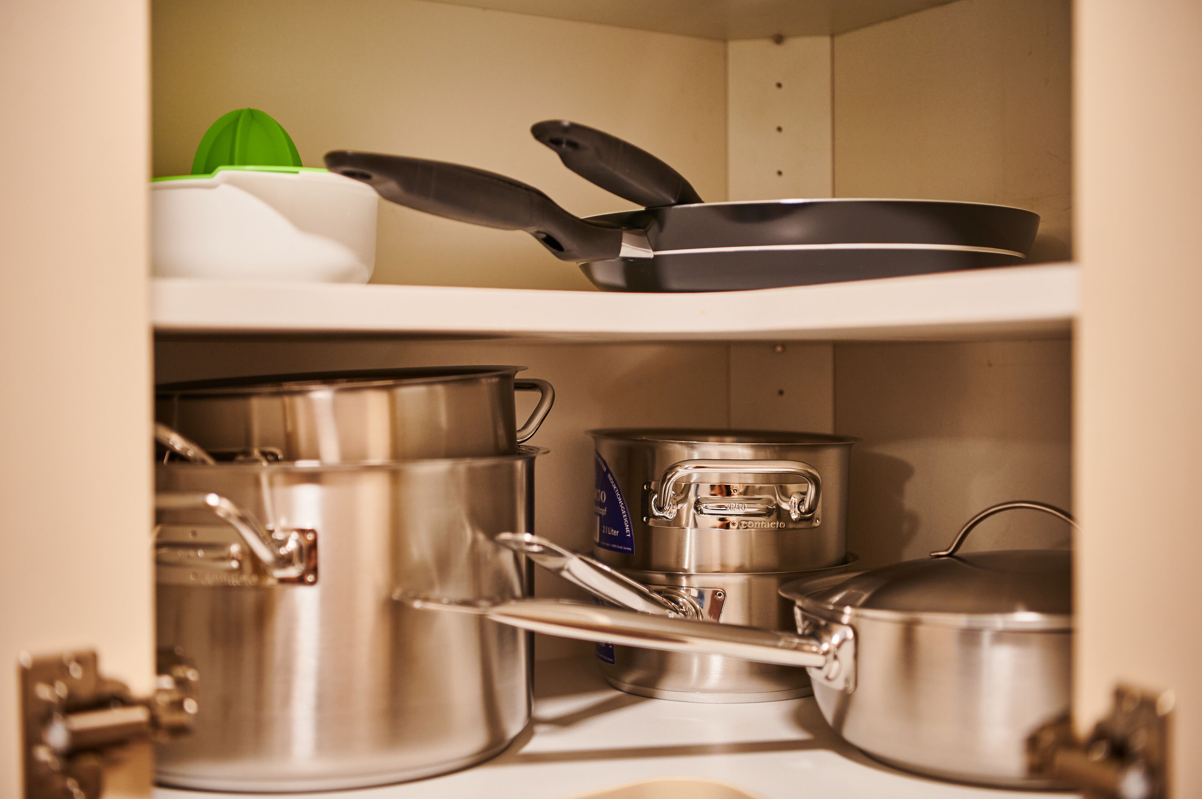 A kitchen with stainless steel cookware, including pots and pans, and a kettle.