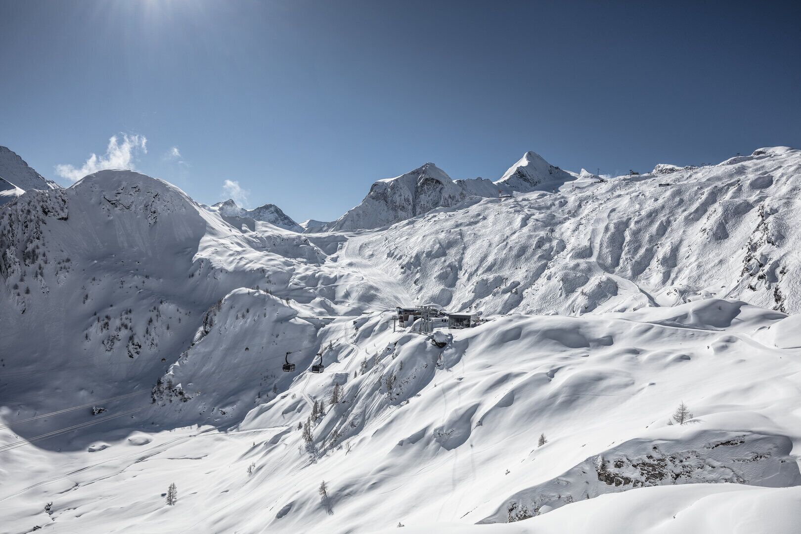 A snow-covered mountain landscape with a ski lift and a building structure.