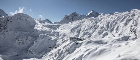 A snow-covered mountain landscape with a ski lift and a building structure.